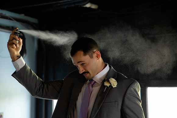 Groomsman spraying hair before wedding ceremony, candid groom prep photo